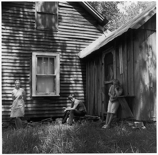 [Woman Leaning Against House Façade, Boy Seated, and Girl Leaning Against Shed]