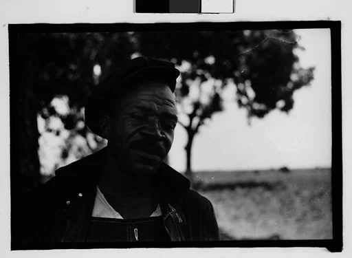 [Man Wearing Cap and Overalls Next to Tree, Hale County?, Alabama]