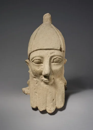 Over-lifesize bearded head wearing a conical helmet