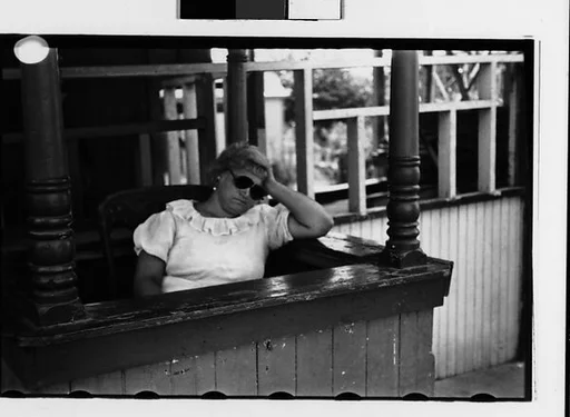 [Two 35mm Film Frames: Sleeping Woman Ticket Taker in Booth at Amusement Park]
