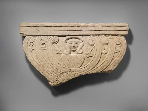 Limestone finial of a funerary stele with volutes and the head of Hathor