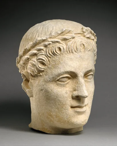 Limestone head of beardless male votary with wreath of leaves