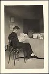 [André Maury Seated in Chair Reading at the Bateau Ivre Bookshop, Juan-les-Pins, France]