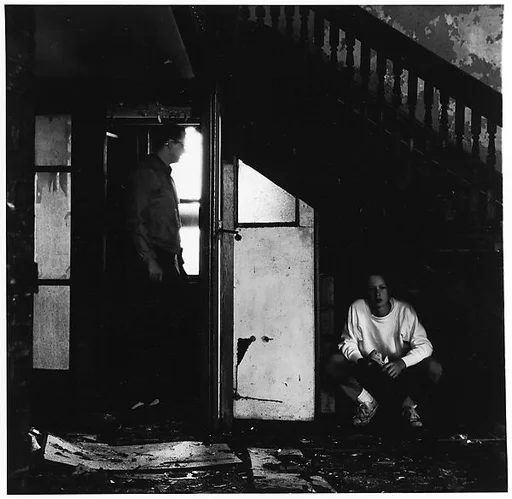 [Darkened Room with Standing Figure and Seated Figure]
