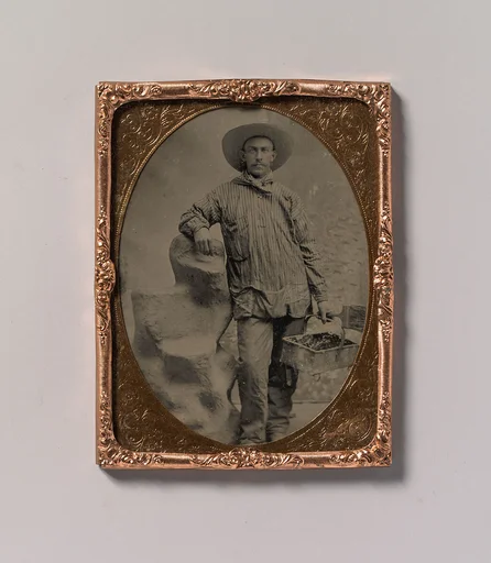 [Workman Holding Brush and Rectangular Tray, Arm Resting on Fake Rock]