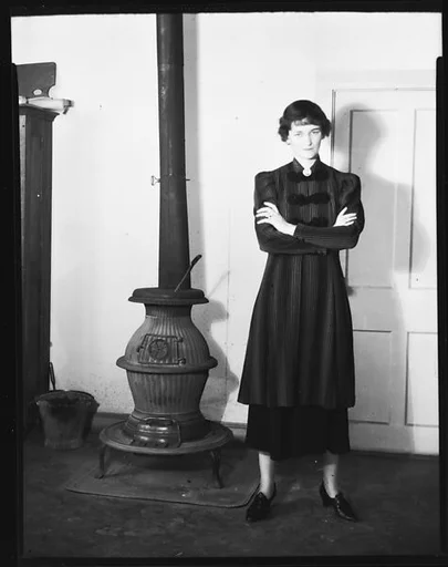 [Jane Fuller Standing Next to Wood Stove, Bedford, New York]