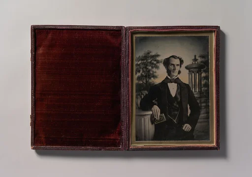 [Man Holding Book, Standing Before a Painted Scenic Backdrop]