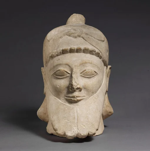 Limestone head of a bearded male wearing a conical helmet