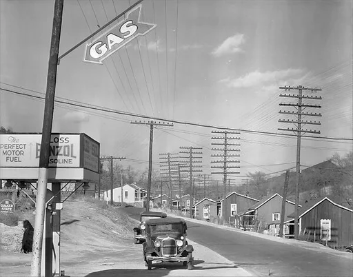[Roadside Gas Station with Parked Cars and Row of Miners' Houses Across Street, Lewisburg, Alabama]
