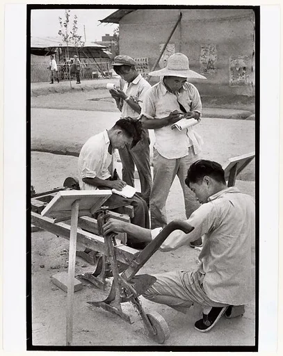 Visitors take notes on a peasant invention at National Farm Implements Exhibit, Peking