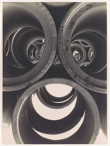 [Water Pipe Abstraction; View through Circular Ends of 3 Stacked Pipes onto Rows of Stacked Pipes in Background]