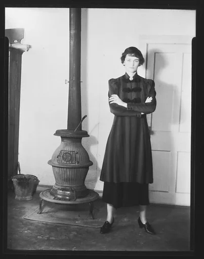 [Jane Fuller Standing Next to Wood Stove, Bedford, New York]