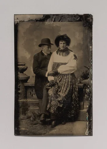 [Two Men, One Dressed in Women's Attire, Holding Hands]