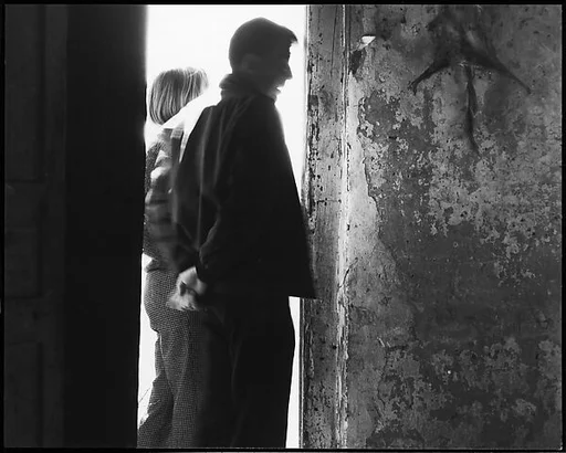 [Guy Davenport and Unidentified Woman in Doorway with Stretched Animal Carcass on Wall]