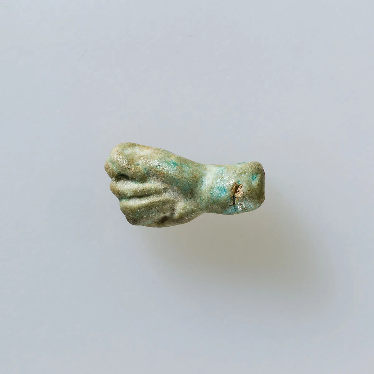 Amulet of fist with thumb thrust between first two fingers — Unknown