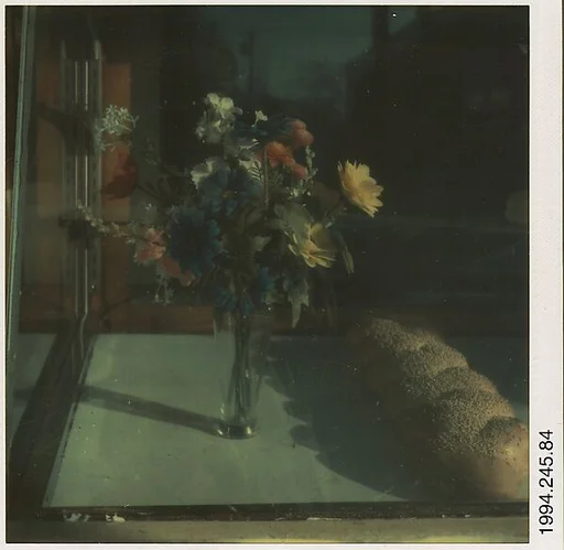[Window Display: Vase of Flowers and Loaf of Bread]
