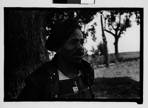 [Man Wearing Cap and Overalls Next to Tree, Hale County?, Alabama]