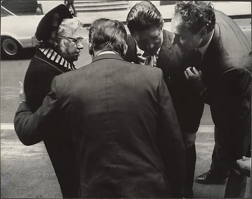[Woman in Hat Conversing with Three Men in Suits, on Street, New York]