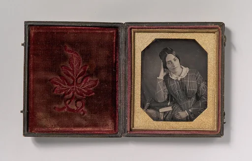 [Young Woman with Elbow Resting on Small Pile of Books and Head on Hand]