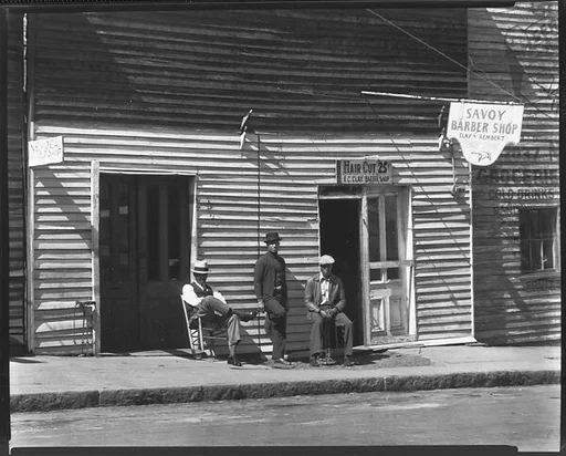 [Men on Sidewalk in Front of New Deal and Savoy Barber Shops, Vicksburg, Mississippi]