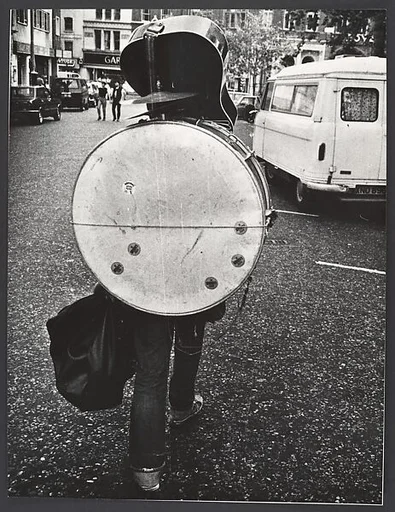[Man From Behind Carrying Guitar and Drum Set, Great Britain]