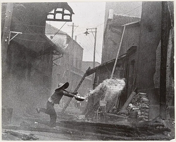 After incendiary bombardments, a woman tries futilely to extinguish the fire. Hankow — Robert Capa