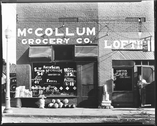 [Main Street Façades of McCollum Grocery Company and Loftis Cafe with Man in Doorway, Greensboro, Alabama]