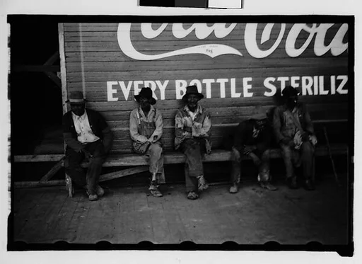 [Men Seated in Front of Coca-Cola Sign on Building Façade, New Orleans Vicinity, Louisiana]