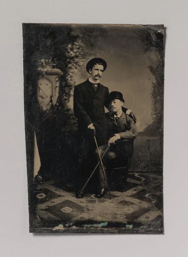 [Two Young Men Crossing Their Walking Sticks]