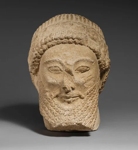 Limestone head of a bearded male with a wreath of flowers