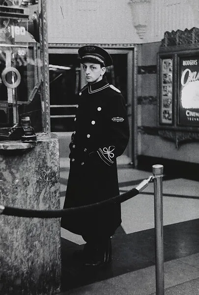 Movie theater usher standing by the box office, N.Y.C. — Diane Arbus
