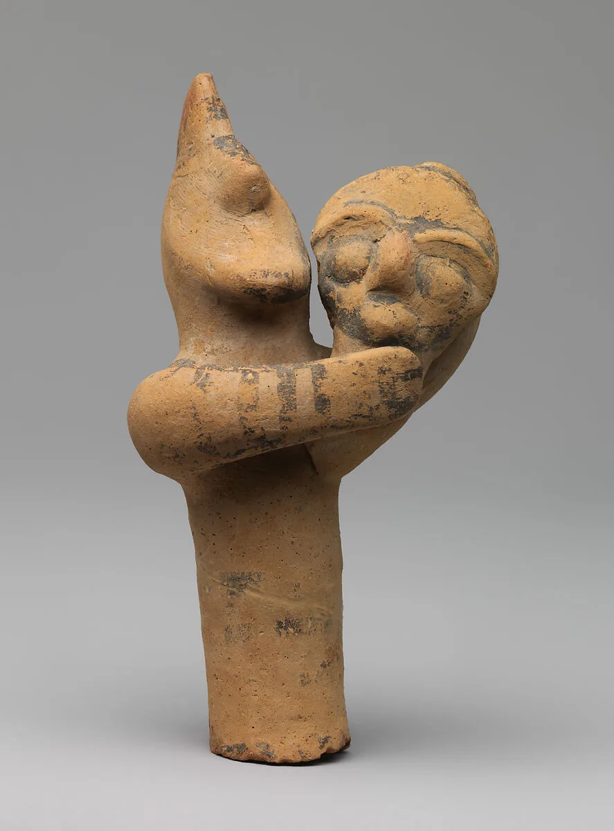 Terracotta statuette of a male figure holding the head and neck of a mask or image — Unknown