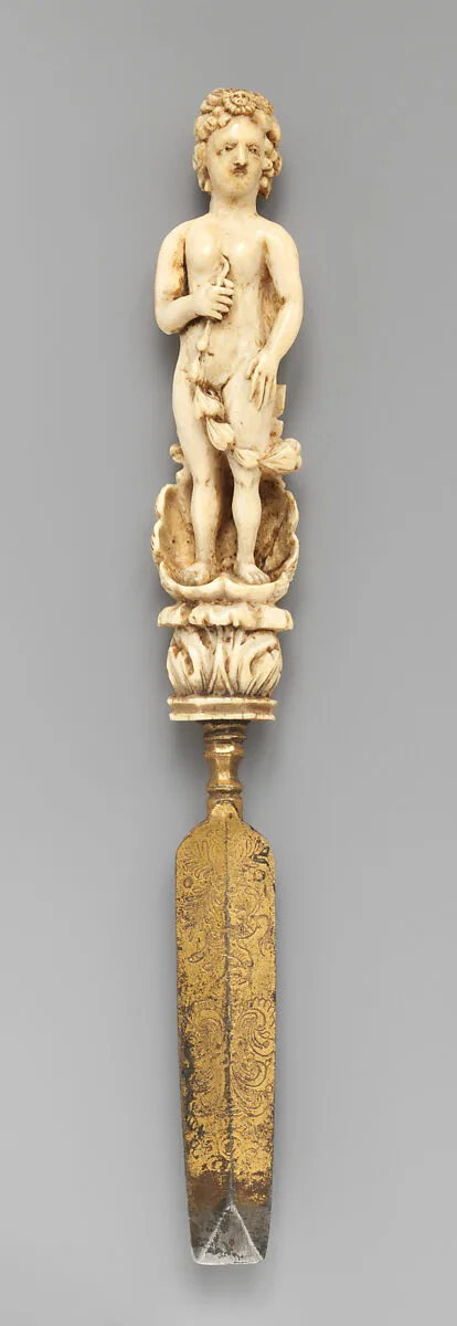 Paper knife with carved handle of nude with sun in hair standing in a half shell holding a swag — Unknown